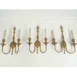 A group of three gilt metal twin branch wall sconces, holding candlesticks but wired, although