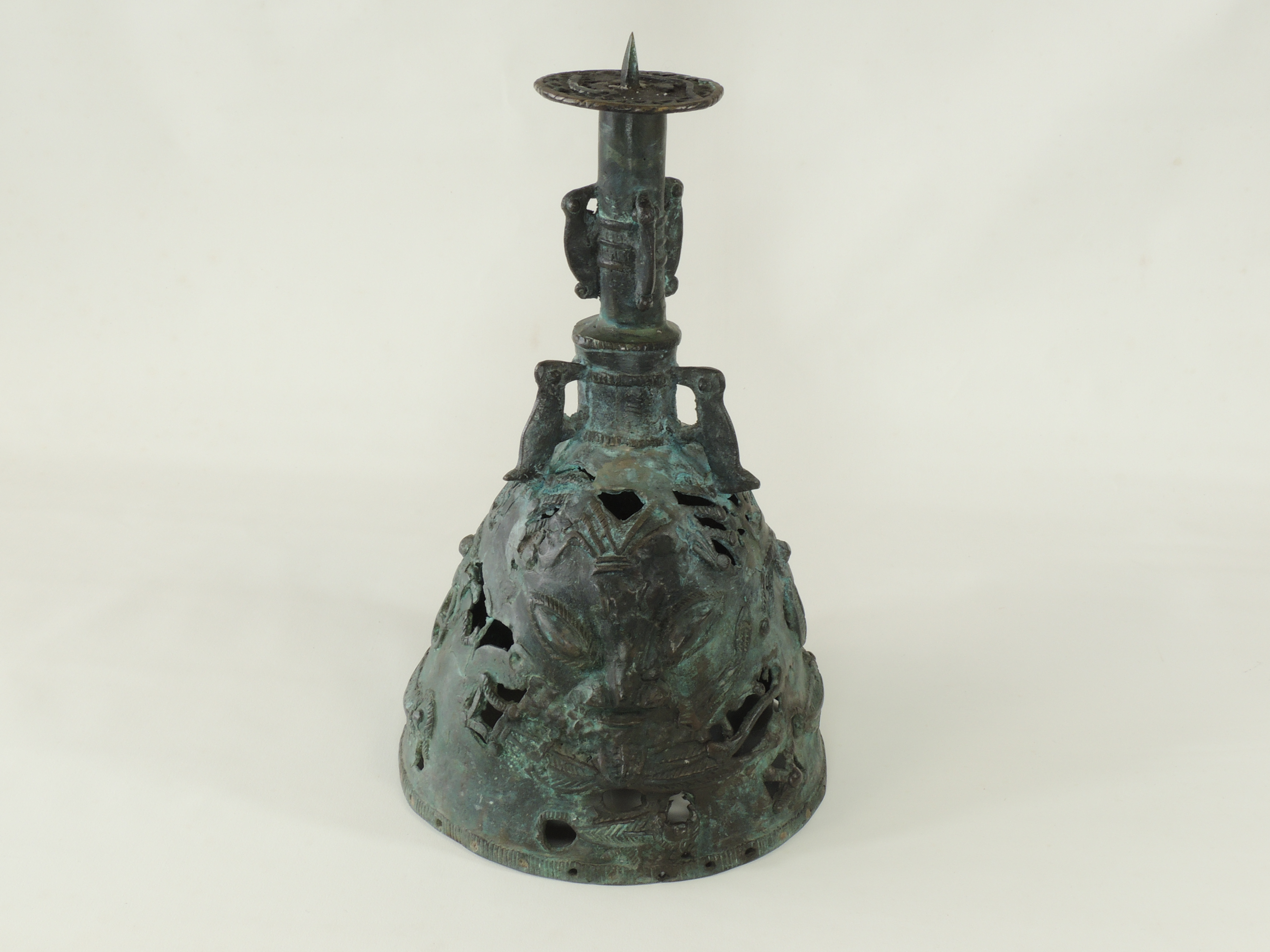 A Benin bronze style bell, with three handles in the form of mythical creatures, twin mask faces and