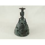 A Benin bronze style bell, with three handles in the form of mythical creatures, twin mask faces and