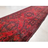 A diamond central patterned runner on dark red ground, 82cm x 300cm