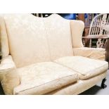 Two seater upholstered wing back settee, set on claw and ball feet to the front. Floor to cushion