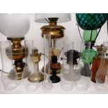 A quantity of various 20th Century oil lamp bases, shades, reservoirs and glass chimneys, to include