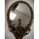 A gilt oval candelabra mirror with triple branch, with acanthus leaves and scrolling floral