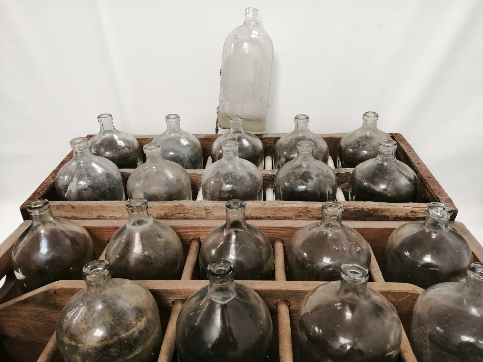 Two vintage wooden crates, each with ten compartments housing ten glass bottles, the metal mounted