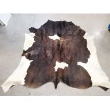 A cow hide floor covering, of brown and cream colour, 230cm x 210cm