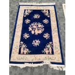 A Peking Oriental rug with precious objects and botanical sprays, on a dark blue ground, with