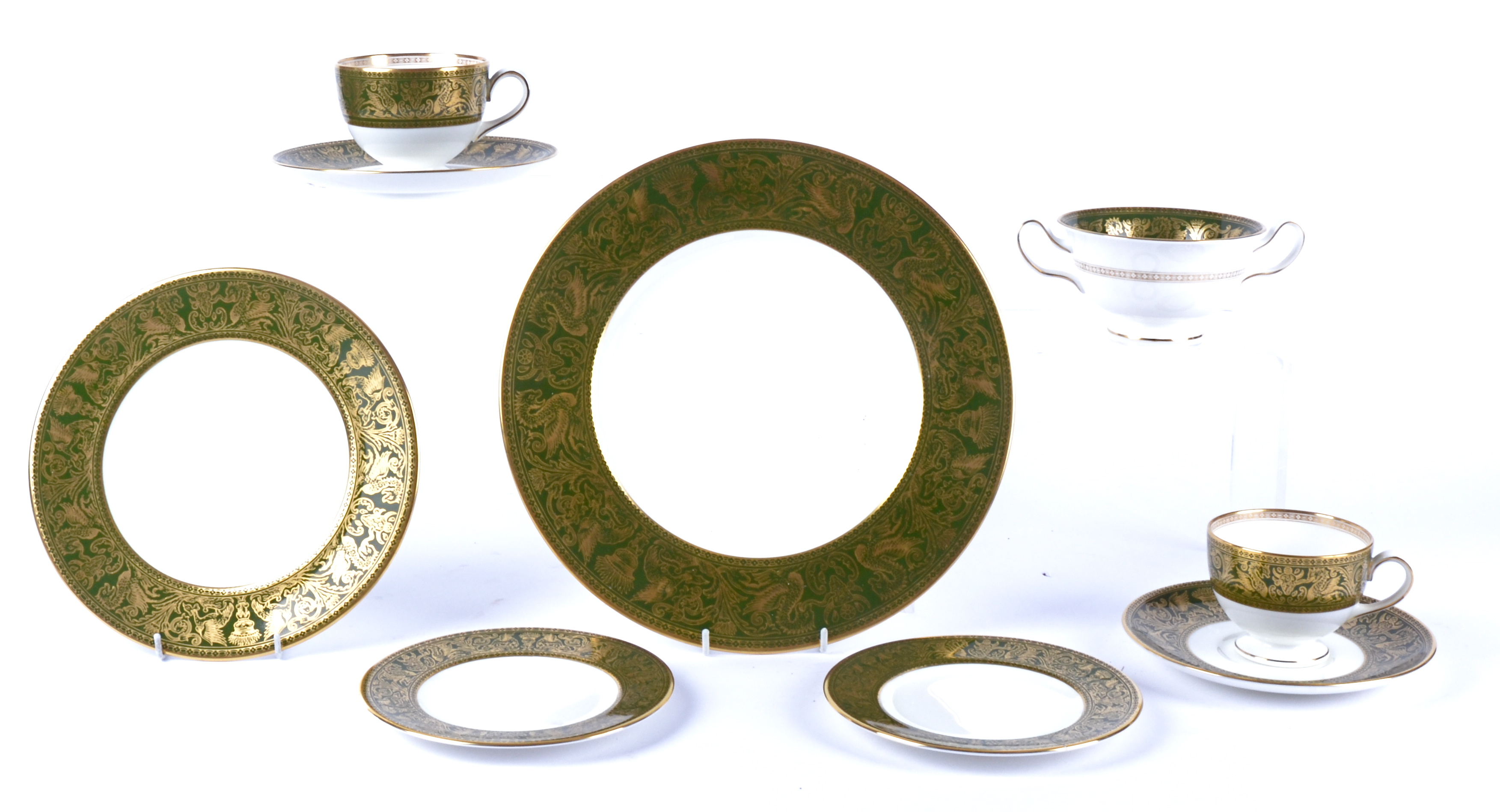 A Wedgwood porcelain part dinner service, decorated with a wide green border with gilt decorations