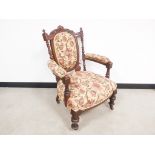 19th Century walnut arm chair, upholstered in a floral pattern on a dark cream ground. Carved and