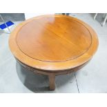 A contemporary oriental style hardwood table, circular grooved top, carving to frieze raised on