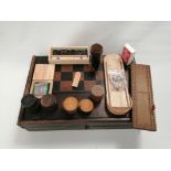 A boxed gaming set with chess board exterior opening to reveal a quantity of associated items, to