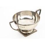 A George V silver footed bowl from William Hutton & Sons, the twin handled circular bowl on a square