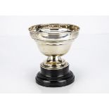 A George V silver footed bowl, on black painted circular wooden base, 4.15 ozt, bent, dented and