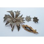 A silver and marcasite flower head brooch, a pinchbeck seed pearl and enamel mourning brooch and a