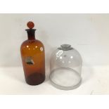 An early 20th century bell shaped clear glass cover, together with an amber Metholated Spirits