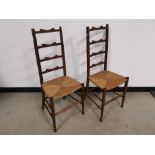 Pair of oak ladder back chairs, having rush ropework seats.