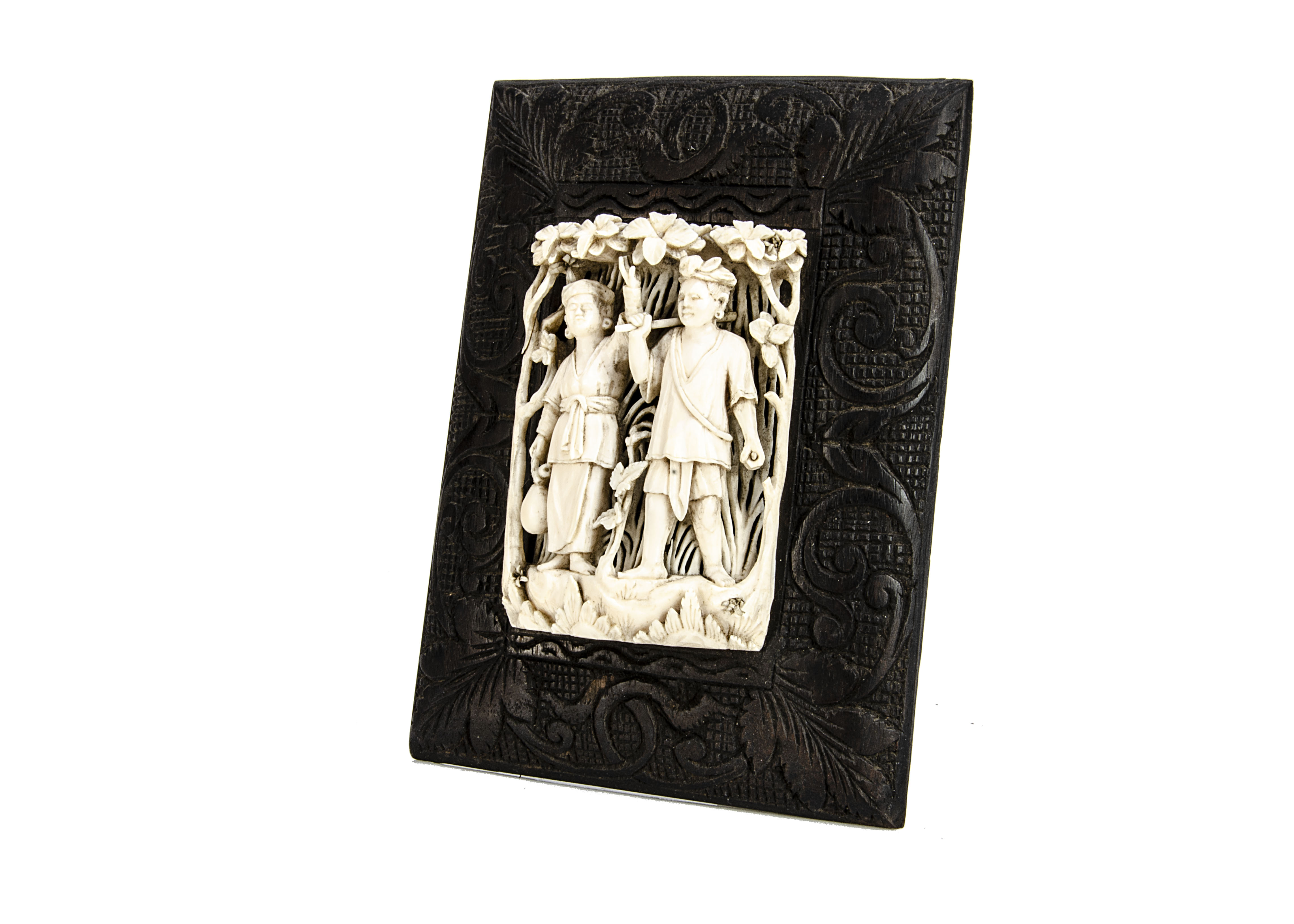 A late 19th century Indian carved ivory decoration, with two figures in a floral setting, mounted on