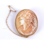 A cameo brooch featuring a woman with flowers in her hair, set in a yellow metal surround,