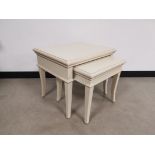 Modern painted nest of two tables, painted off white, raised on sabre style supports. Larger table -