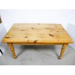 A contemporary waxed pine kitchen table, rectangular top raised on four round turned supports, 152cm