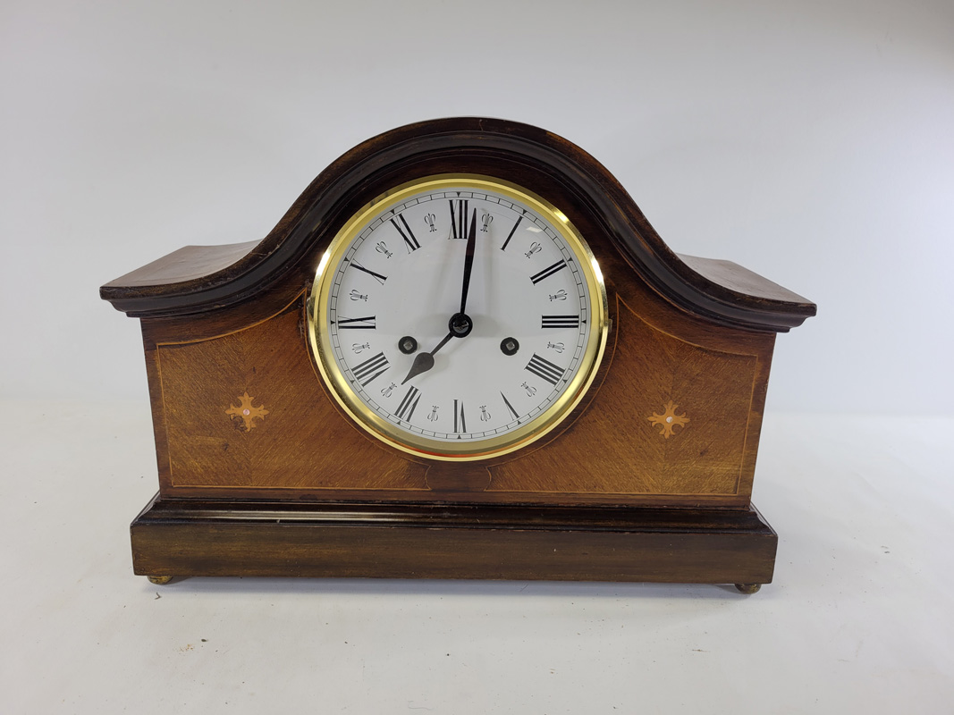 A 20th Century mahogany mantelpiece clock raised on four brass ball feet, with enamel dial and Roman