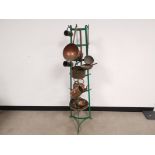 A towering green painted metal tripod display rack with hooks, covered in early 20th Century