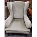 Upholstered wing back arm chair, Raised on pad feet supports to the front, set on four castors. 76cm