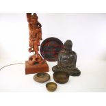 A carved wooden table lamp in the form of an eastern fisherman, together with a cast metal Buddha