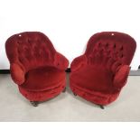 Pair of low button back arm chairs, finished in a deep red farbric, raised on turned supports and