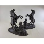 A pair of cast metal figures of bucking horses being pulled by semi clad figures, 31cm x 32cm