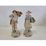 A pair of Continental porcelain figures with plentiful baskets of produce, one male, one female,