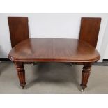 Mahogany extending dining table, Raised on reeded supports set on castors. Together with two