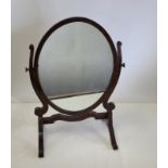 An oval mahogany cheval mirror raised on two scrolling feet, height 60cm, together with another