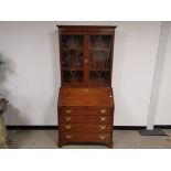Mahogany bureau bookcase, With glazed double doors to the upper section, drop down front and four