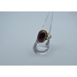 A 9ct gold garnet cabochon dress ring, oval stone in rope twist setting, ring size N, 5g