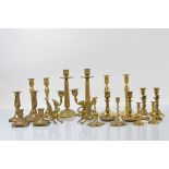 A quantity of brass candlesticks, including a pair of griffin examples with glass eyes, a pair of
