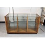 A glazed display case, with glass top and front, with three banks of three tapering glass shelves,