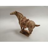 A Chinese earthenware Tang style tomb horse, with textured saddle, raised on a rectangular base,
