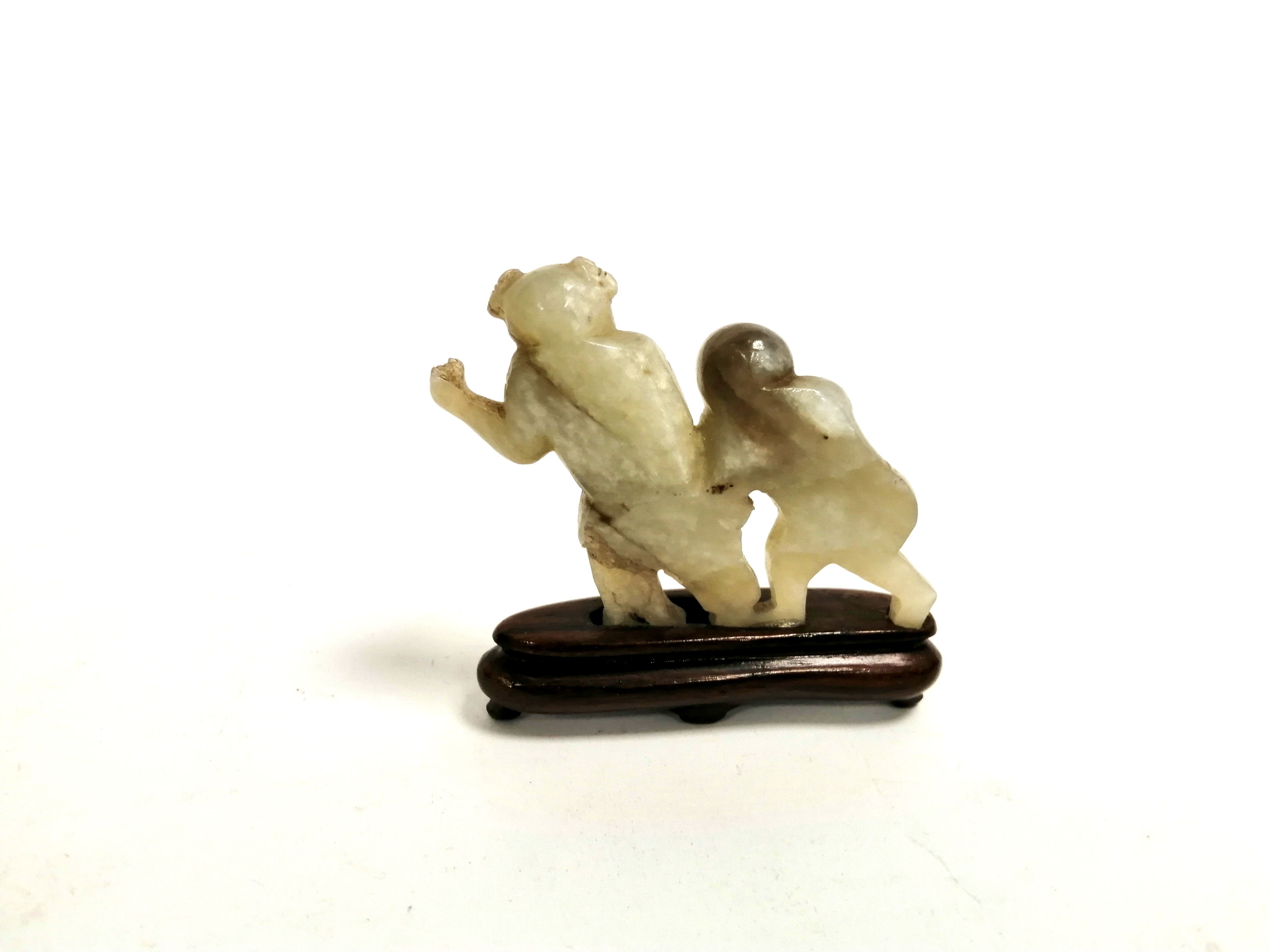 A Chinese hardstone carving of children holding hands, raised on a wooden stand, height 5cm - Image 2 of 2