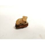 A Chinese hardstone carving of a dog, raised on a wooden stand, height 4cm