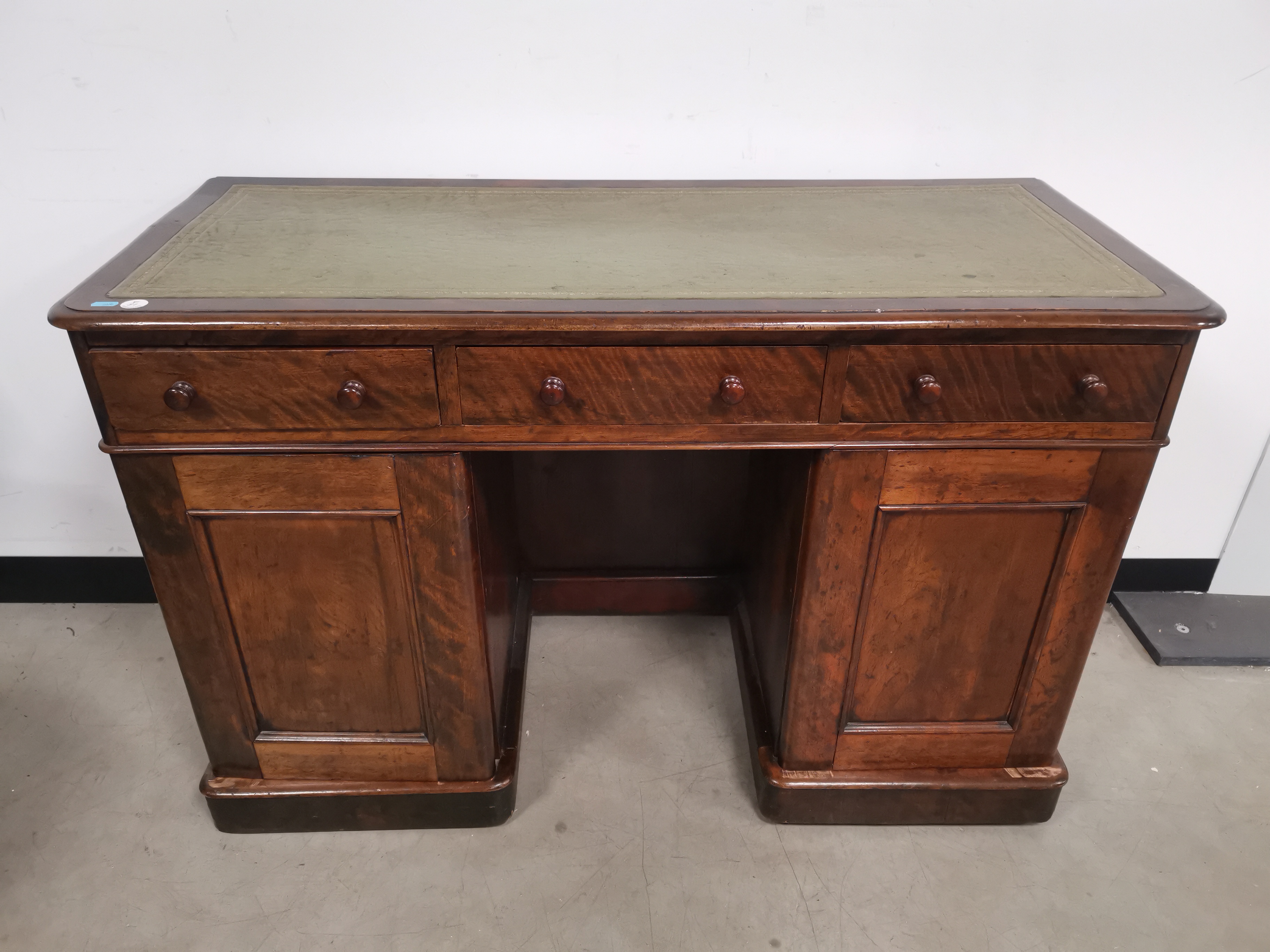 Walnut veneered green leather topped twin pedestal writing desk, with three draws to freize,