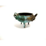 A heavily patinated brass tripod censer, probably Chinese, of twin handled form with prunus