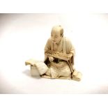 A Japanese Meiji period ivory okimono of a seated figure with an abacus and open book, with
