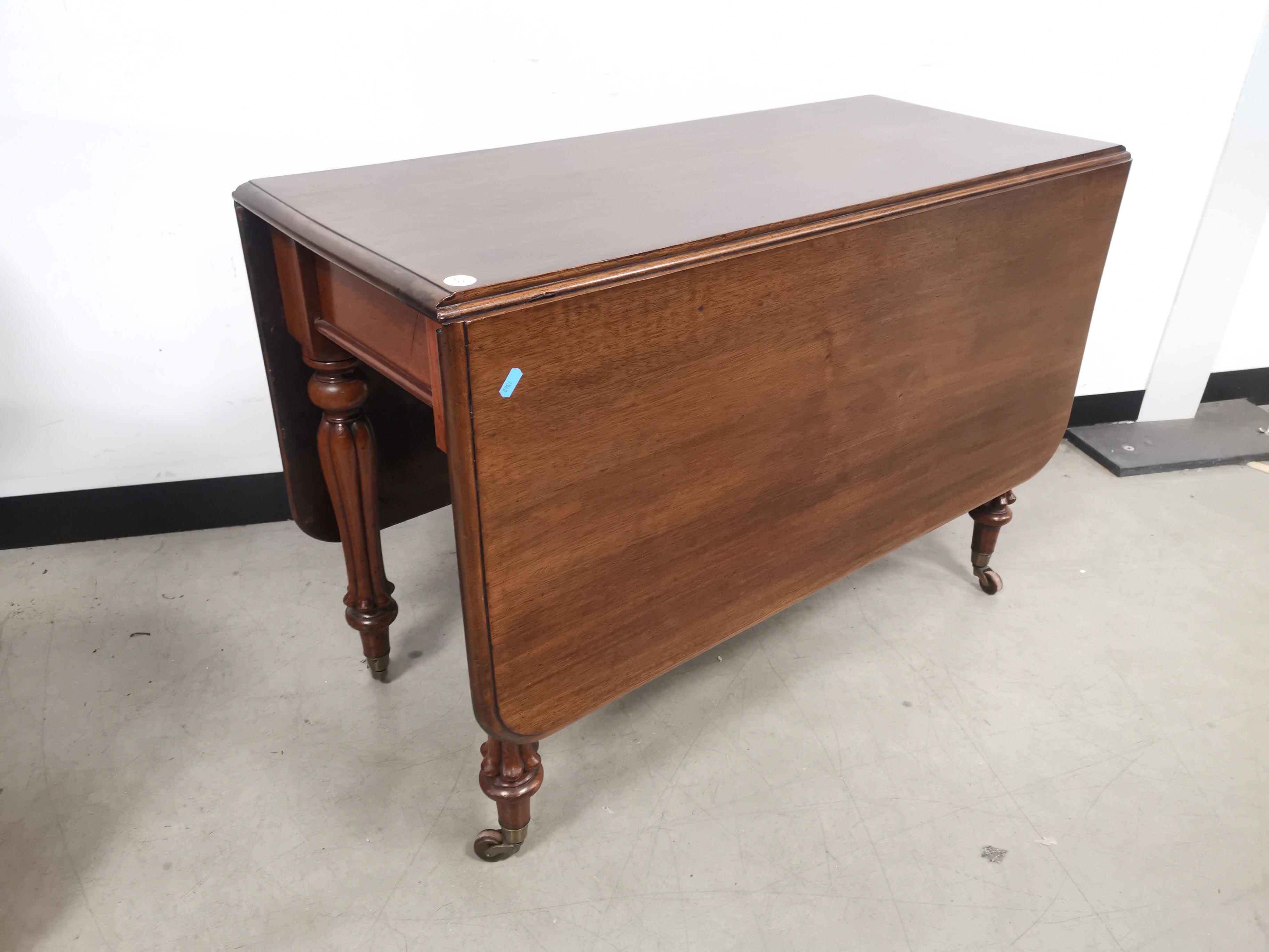 19th Century mahogany drop leaf table, raised on reeded supports and castors. Having later top.