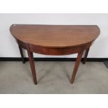 Mahogany demi lune table, raised on square supports.