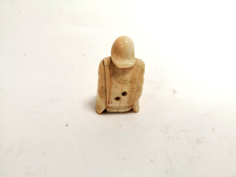 A miniature Japanese ivory okimono of a seated male clasping a creature, with two holes for - Image 3 of 4