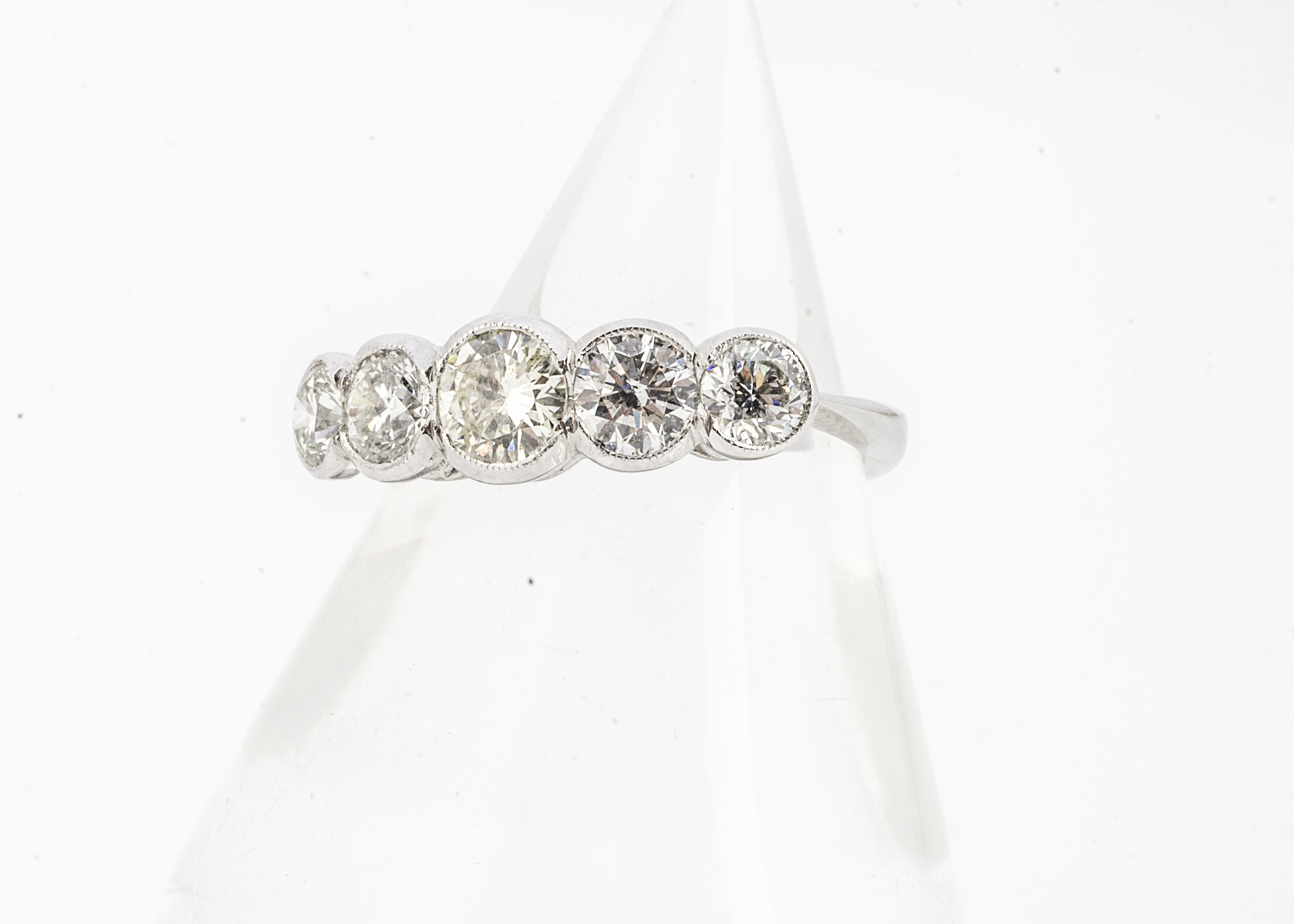 A diamond five stone platinum set dress ring, brilliant cuts in rubbed over settings on white