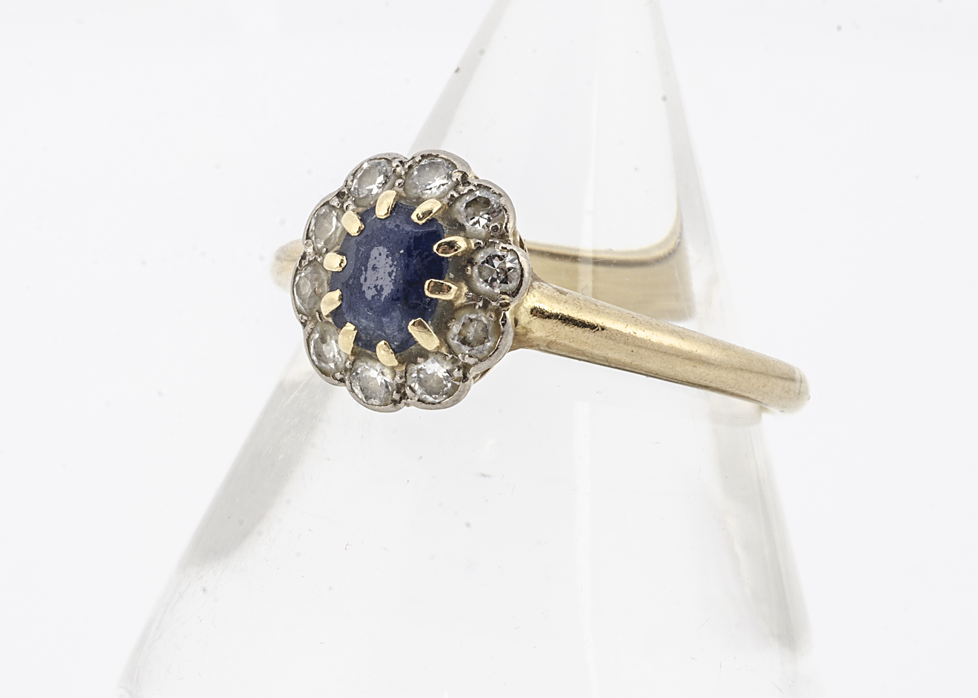 A sapphire and diamond cluster ring, the oval mixed cut sapphire heavily abraded, in claw setting