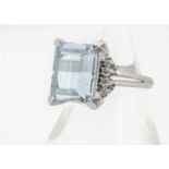 An aquamarine and diamond dress ring, the mixed step cut aquamarine flanked by brilliant cut