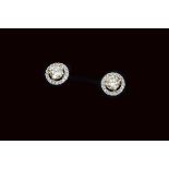 A pair of certificated yellow diamond brilliant cut colourless diamond ear studs, the round