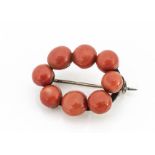 A continental coral and white metal oval bead brooch, the bouton polished coral beads on a white